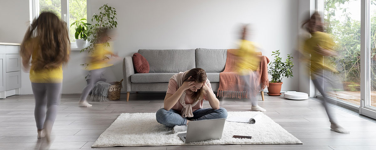 Das Foto zeigt eine gestresste Mutter die vor ihrem Laptop sitzt.